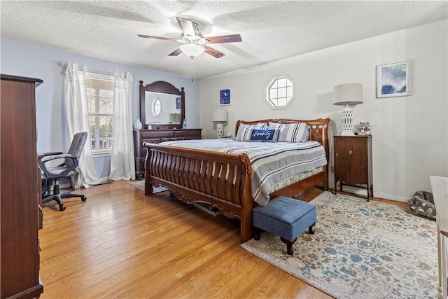 bedroom with ceiling fan, a textured ceiling, and light wood-style flooring