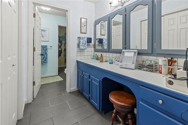 bathroom with backsplash, baseboards, toilet, and vanity