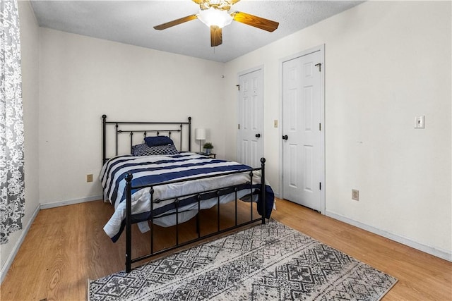 bedroom with light wood-type flooring, baseboards, and ceiling fan
