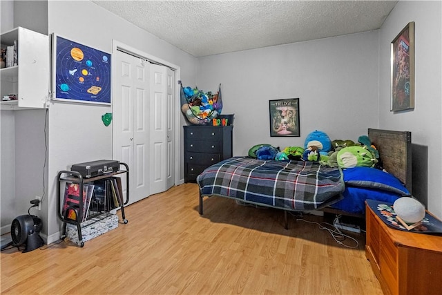 bedroom with wood finished floors, a textured ceiling, and a closet