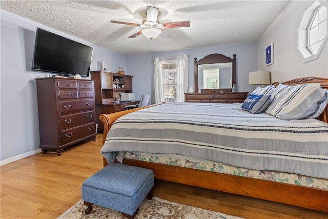 bedroom featuring ceiling fan, wood finished floors, and a textured ceiling