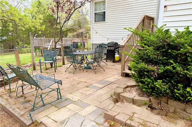 view of patio featuring fence, outdoor dining space, and a grill