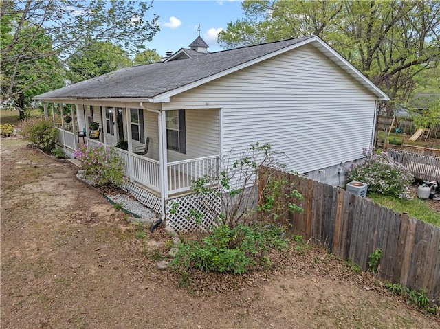 view of property exterior with fence, a shingled roof, and covered porch