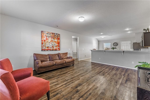 living room with a textured ceiling and dark wood-type flooring