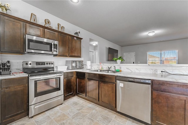 kitchen with sink, dark brown cabinetry, stainless steel appliances, and tasteful backsplash