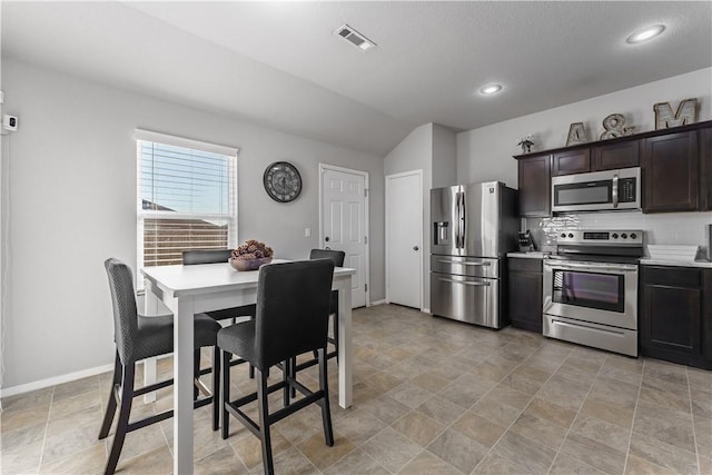 kitchen with decorative backsplash, dark brown cabinets, stainless steel appliances, and lofted ceiling