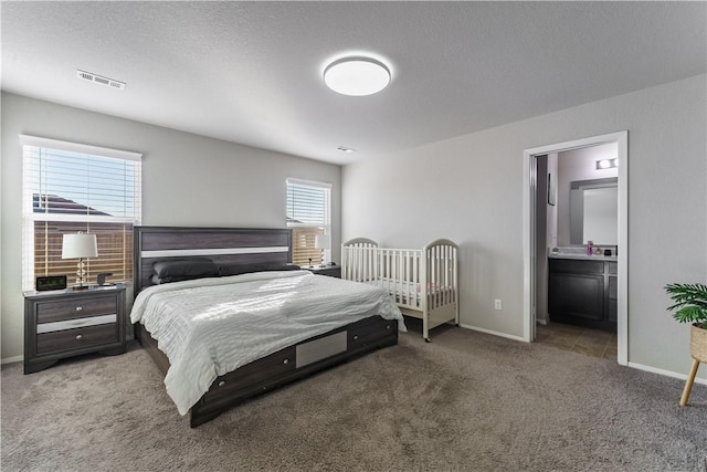 carpeted bedroom featuring multiple windows, ensuite bathroom, and a textured ceiling