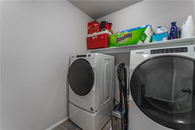 clothes washing area with washing machine and clothes dryer, tile patterned flooring, and a textured ceiling