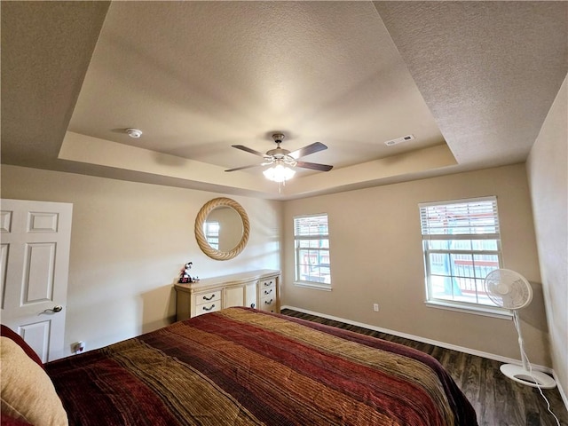 bedroom with a tray ceiling, multiple windows, and ceiling fan