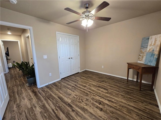 unfurnished bedroom with ceiling fan, a closet, and dark wood-type flooring