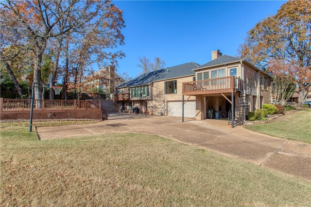 rear view of house featuring a garage, a deck, and a lawn