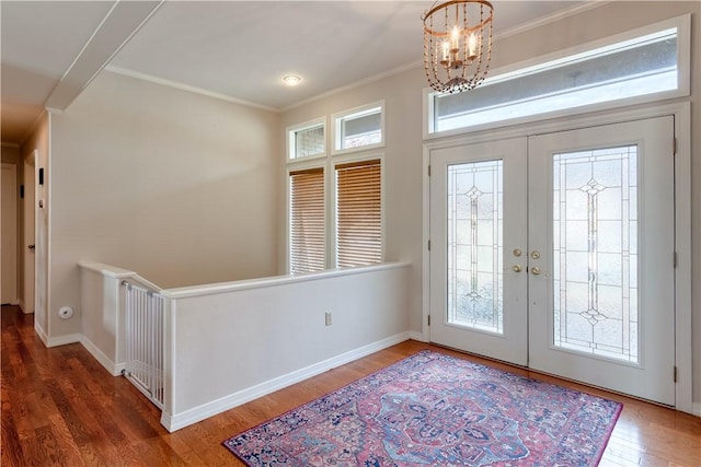 foyer with an inviting chandelier, crown molding, dark wood-type flooring, and french doors