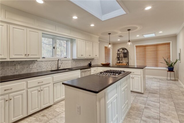 kitchen with a skylight, a center island, tasteful backsplash, pendant lighting, and appliances with stainless steel finishes