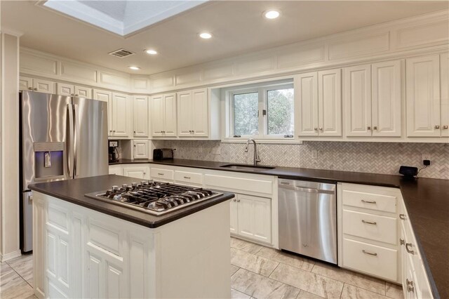 kitchen with white cabinets, a center island, stainless steel appliances, and sink