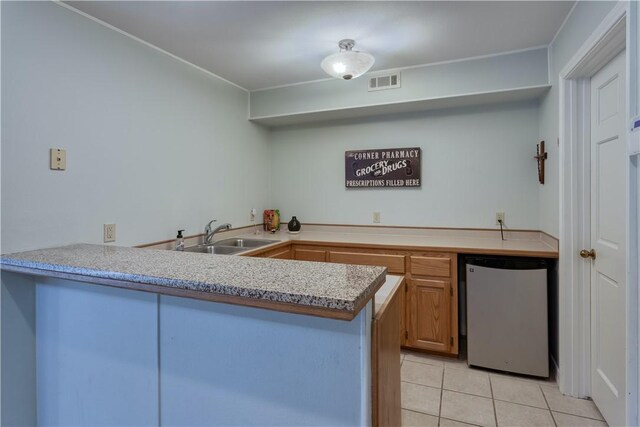 kitchen featuring stainless steel refrigerator, kitchen peninsula, sink, and light tile patterned floors