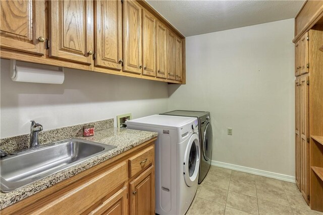 washroom featuring sink, cabinets, washing machine and dryer, a textured ceiling, and light tile patterned floors