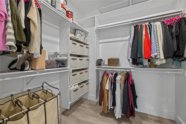 walk in closet with light hardwood / wood-style floors