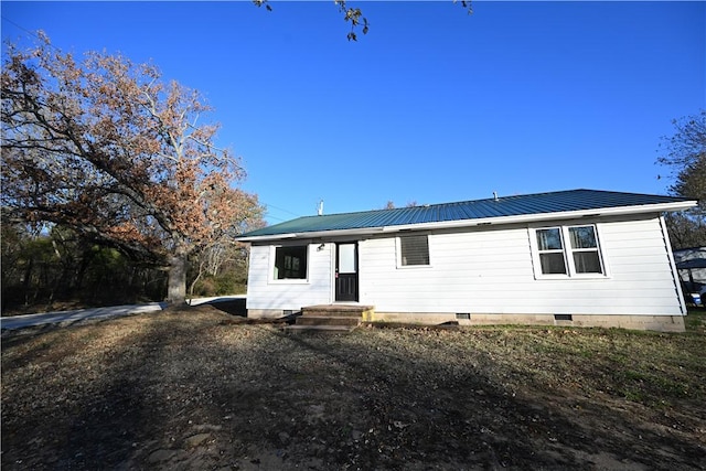 rear view of property with crawl space and metal roof