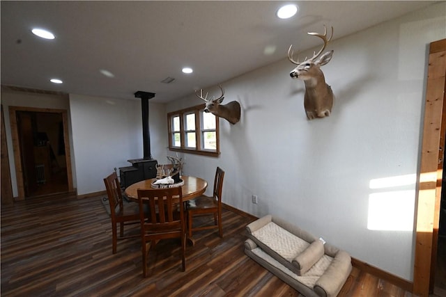 dining space featuring a wood stove and dark wood-type flooring