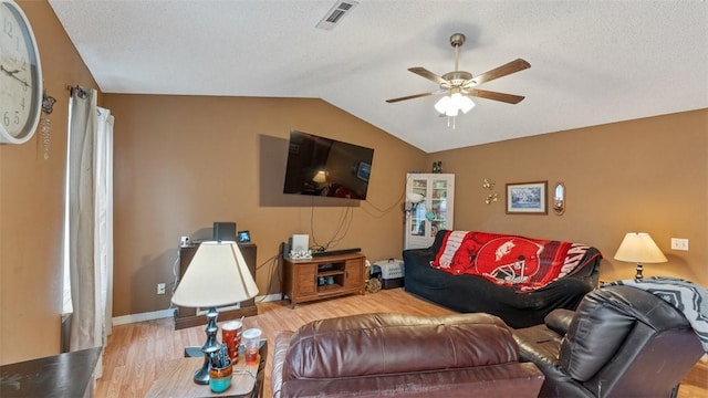 living room with ceiling fan, light hardwood / wood-style floors, a textured ceiling, and vaulted ceiling