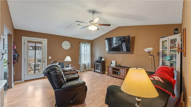 living room featuring a textured ceiling, light wood-type flooring, vaulted ceiling, and ceiling fan