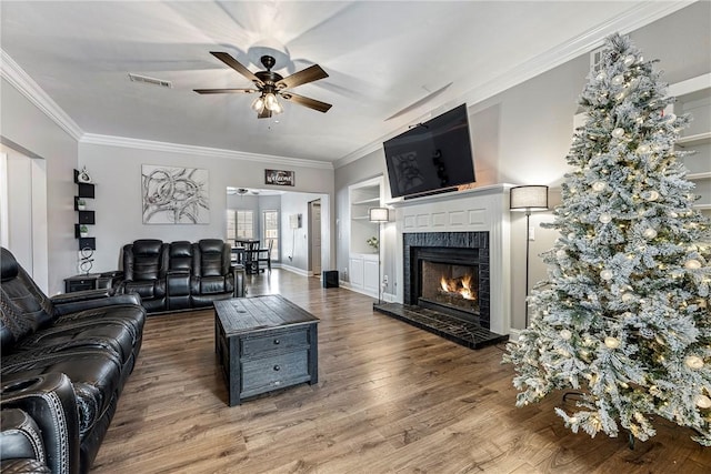 living room with a fireplace, hardwood / wood-style flooring, ceiling fan, and crown molding