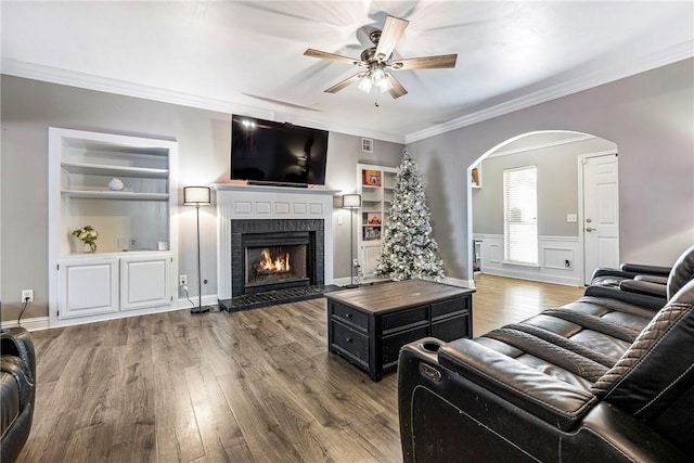 living room featuring ceiling fan, built in features, hardwood / wood-style floors, and ornamental molding