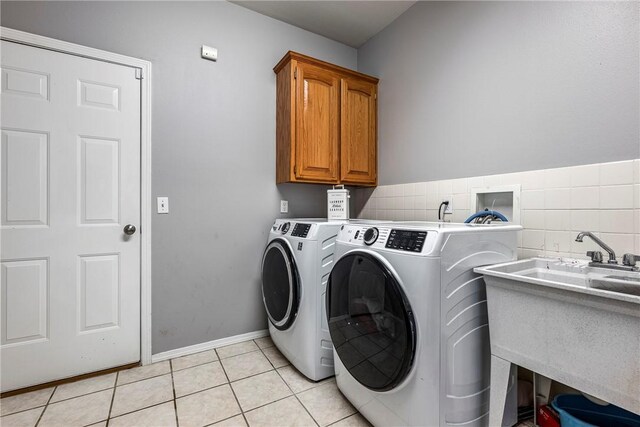 laundry room with cabinets, light tile patterned floors, sink, and washing machine and dryer