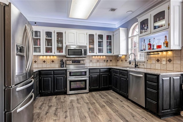 kitchen featuring sink, appliances with stainless steel finishes, light wood-type flooring, white cabinets, and ornamental molding