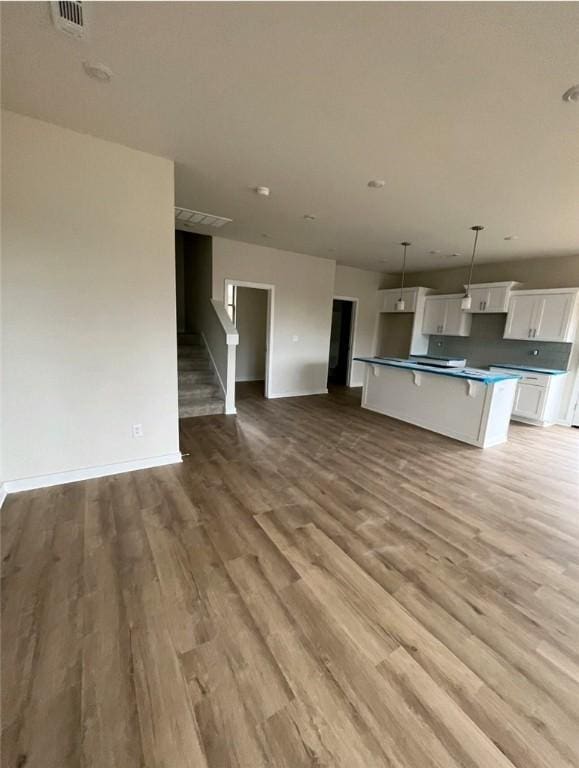 kitchen with white cabinets, a center island, light wood-type flooring, and hanging light fixtures