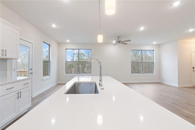 kitchen with white cabinetry, hardwood / wood-style floors, sink, and hanging light fixtures