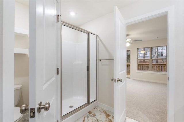 bathroom with ceiling fan, toilet, and a shower with shower door