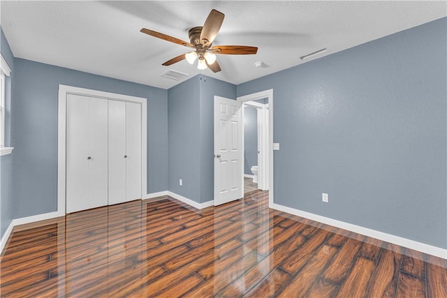 unfurnished bedroom with dark hardwood / wood-style flooring, ceiling fan, a closet, and a textured ceiling