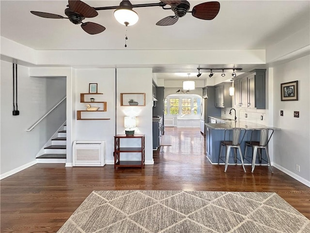 kitchen featuring kitchen peninsula, light stone counters, sink, gray cabinets, and dark hardwood / wood-style floors