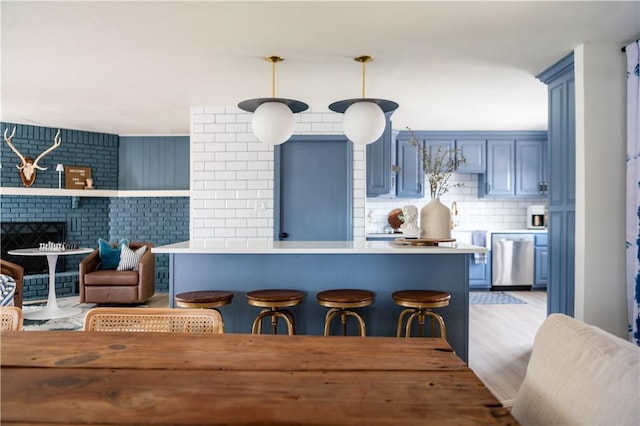 kitchen featuring kitchen peninsula, decorative backsplash, blue cabinets, light hardwood / wood-style floors, and hanging light fixtures