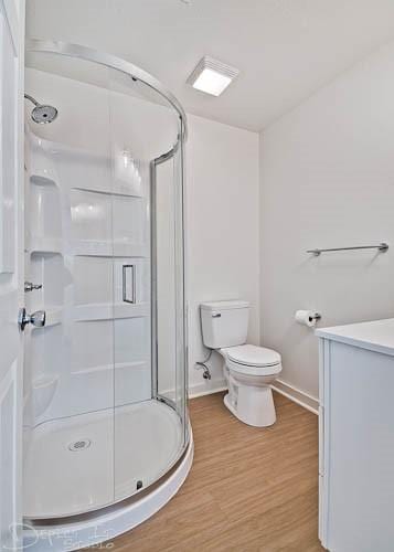 bathroom with hardwood / wood-style floors, toilet, an enclosed shower, and vanity