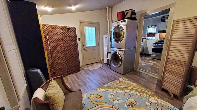 laundry room with a healthy amount of sunlight, hardwood / wood-style floors, and stacked washing maching and dryer