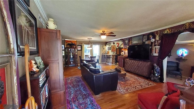 living room featuring hardwood / wood-style floors, ceiling fan, and crown molding