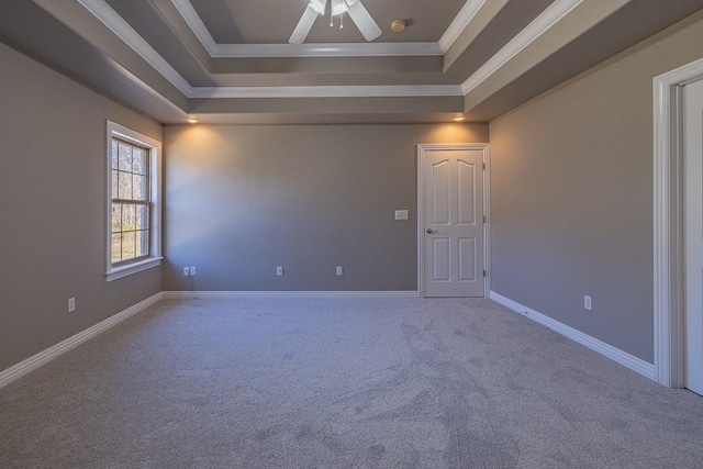 empty room featuring a raised ceiling, crown molding, carpet, and ceiling fan