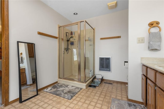 bathroom featuring vanity, heating unit, toilet, and a shower with door