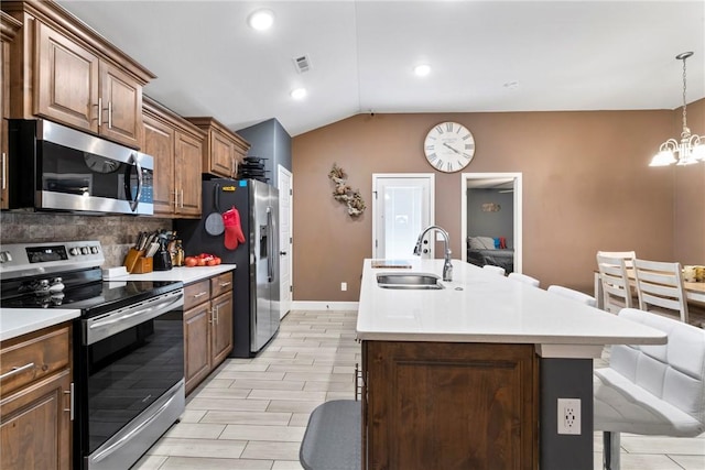 kitchen with sink, a kitchen breakfast bar, lofted ceiling, a kitchen island with sink, and appliances with stainless steel finishes