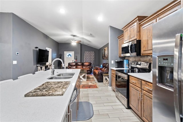 kitchen featuring tasteful backsplash, stainless steel appliances, ceiling fan, sink, and lofted ceiling