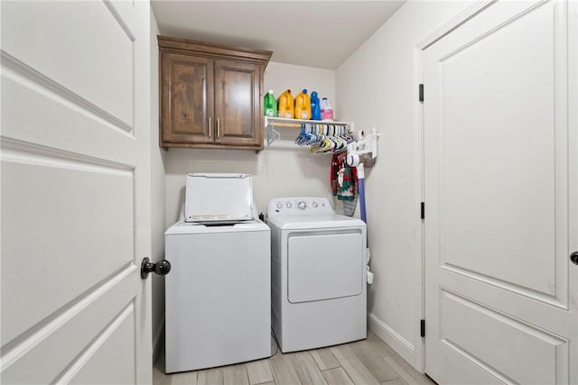 laundry area with cabinets, separate washer and dryer, and light hardwood / wood-style flooring