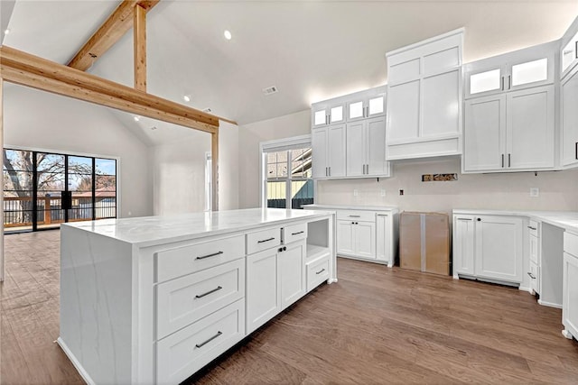 kitchen with plenty of natural light, beam ceiling, a kitchen island, and white cabinetry