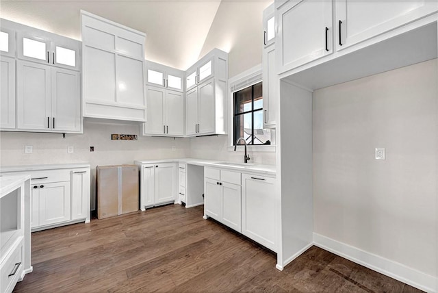 kitchen with vaulted ceiling, white cabinetry, sink, and dark hardwood / wood-style floors