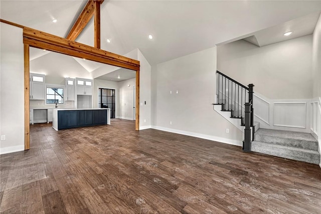 unfurnished living room with beam ceiling, high vaulted ceiling, and dark wood-type flooring