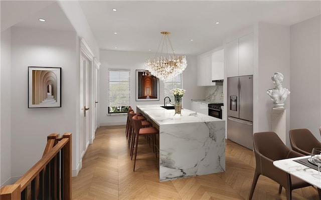 kitchen featuring a kitchen island with sink, stainless steel refrigerator with ice dispenser, decorative light fixtures, white cabinetry, and light parquet flooring