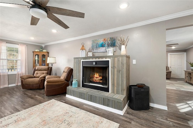 living area with a fireplace, dark wood-type flooring, and ornamental molding