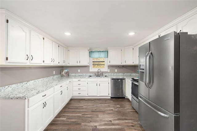 kitchen with appliances with stainless steel finishes, dark hardwood / wood-style flooring, light stone counters, sink, and white cabinets