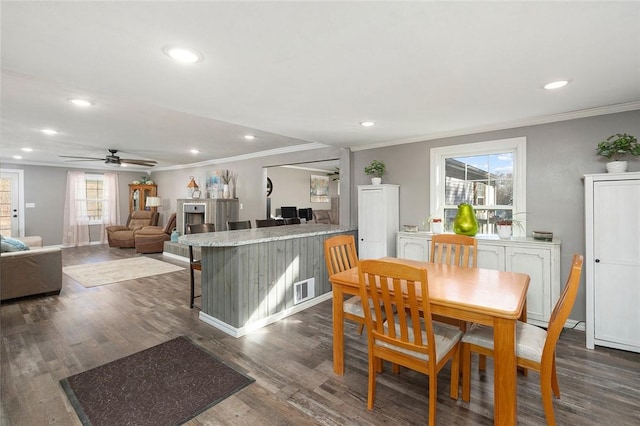 dining area featuring ornamental molding, dark hardwood / wood-style flooring, ceiling fan, and a healthy amount of sunlight